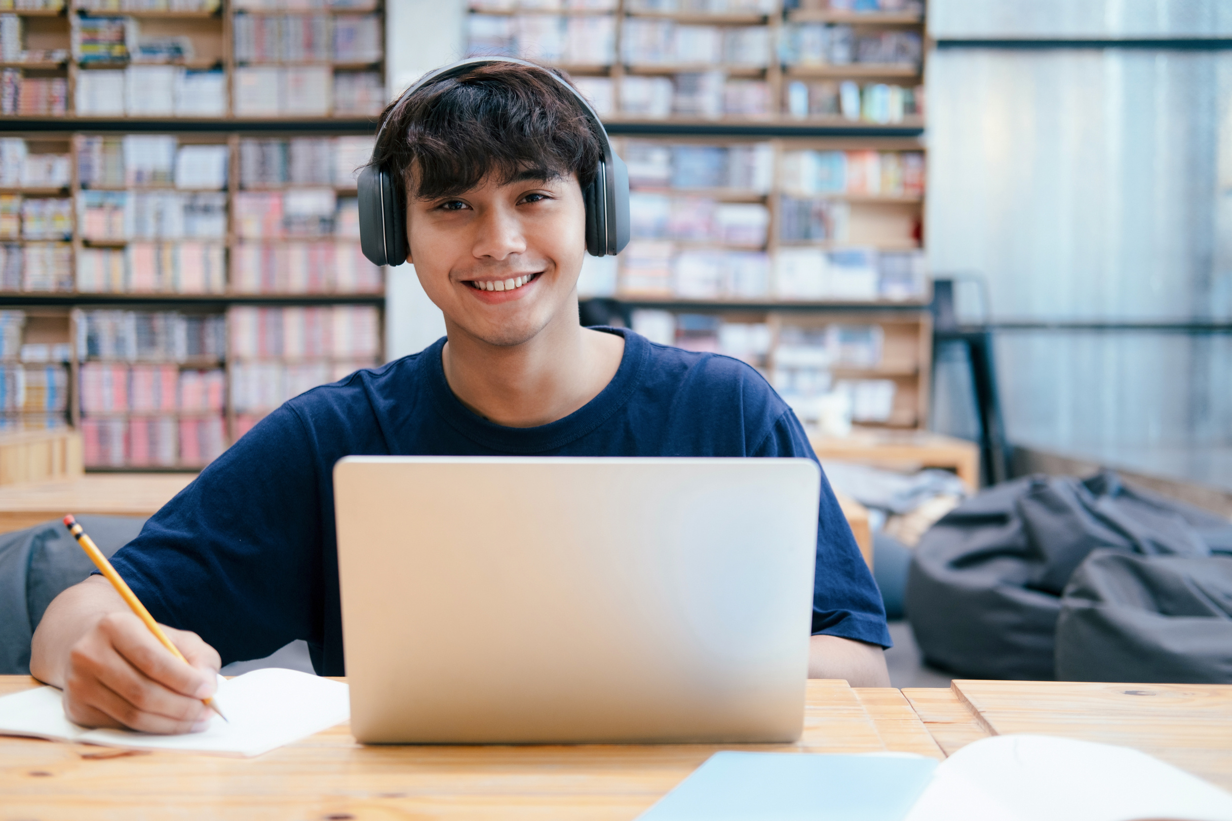 Young College Student Studying in Library with Laptop